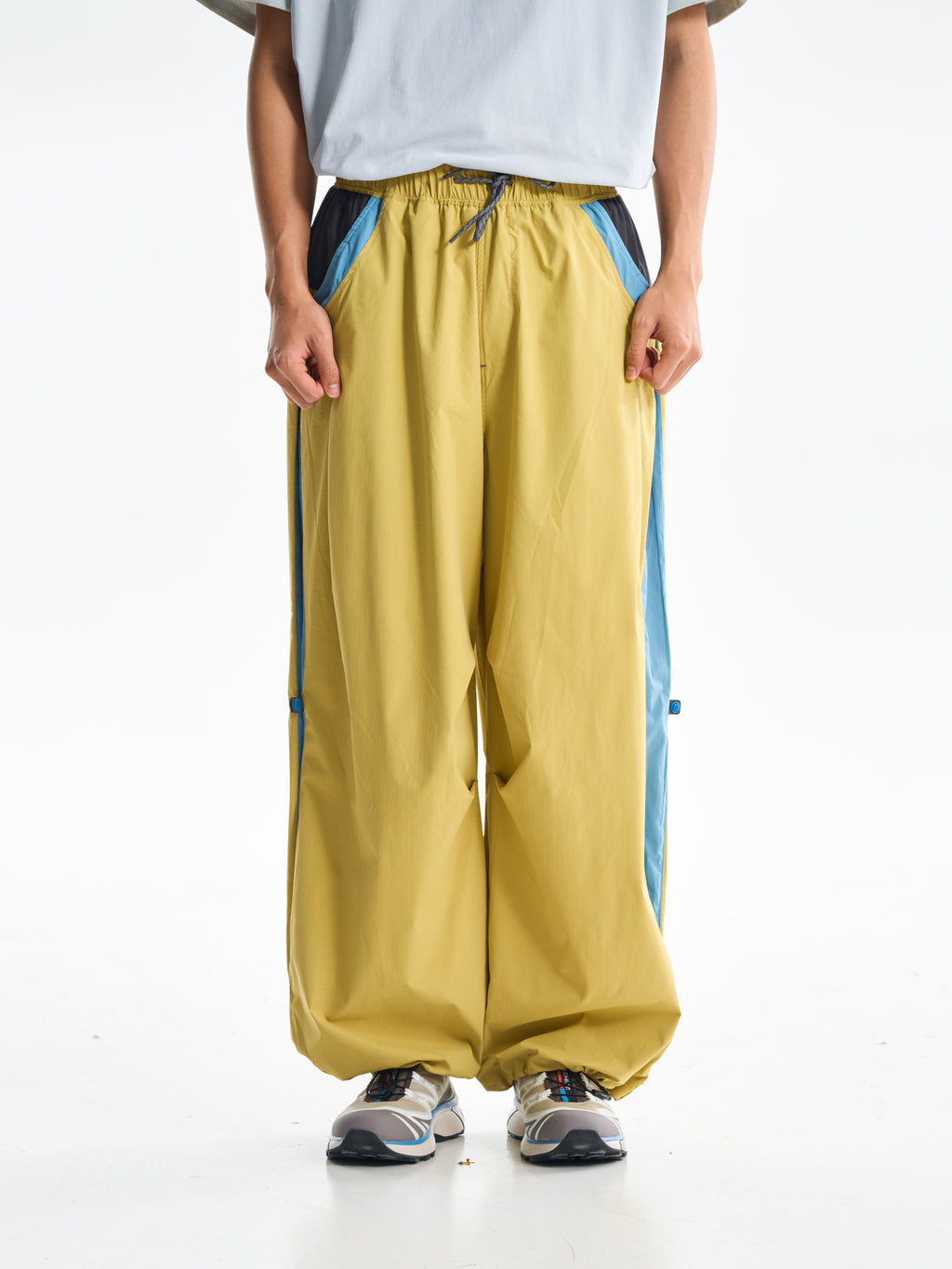 Yellow hiking pants — front view showing the drawcord waist and blue pocket trim