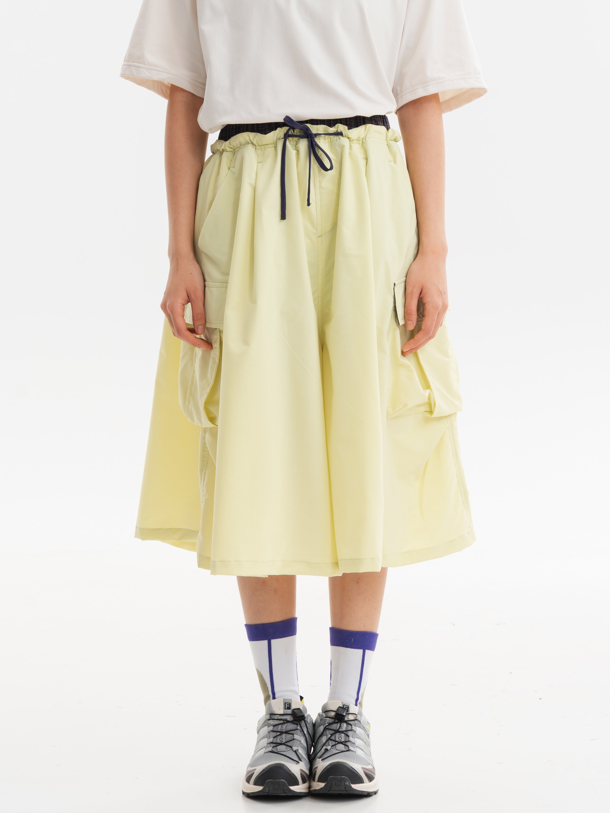 Yellow hiking capri pants — front view with a dark drawcord and wide cropped legs