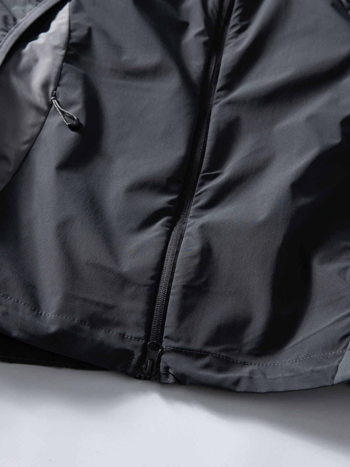 Gray jacket — lower front zipper and pull at the stitched hem