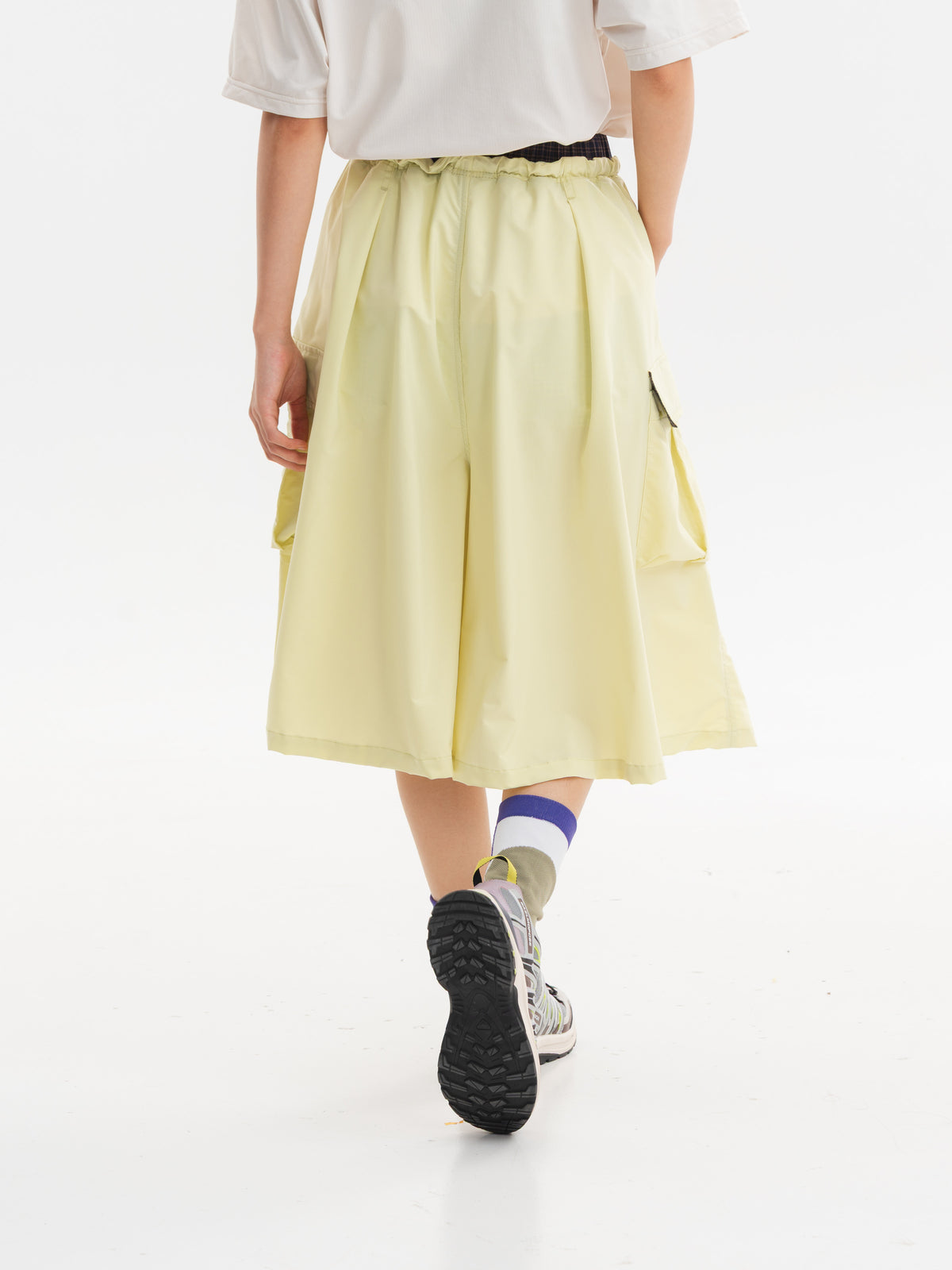 Yellow hiking capri pants — rear walking view showing the gathered waist and flowing leg shape