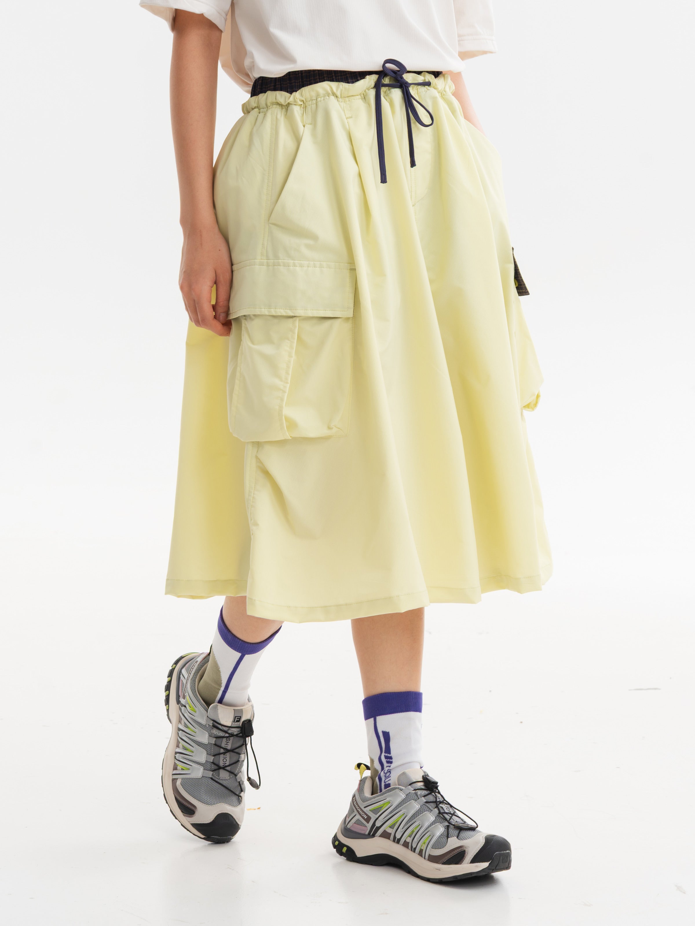 Yellow hiking capri pants — side stepping view showing the cargo flap and wide leg opening
