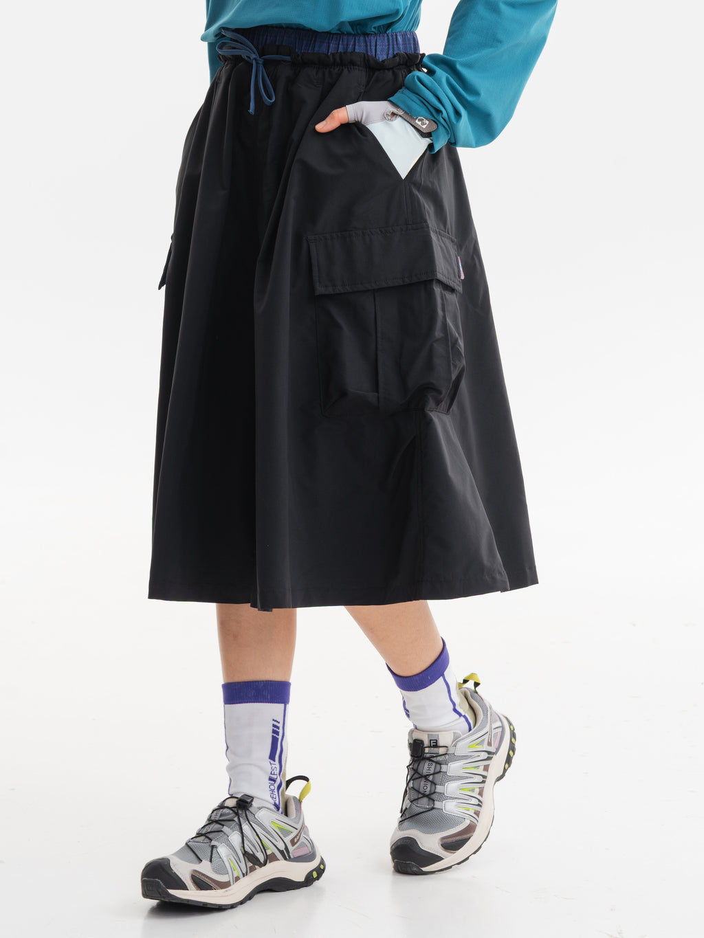 Black hiking capri pants — walking side view with one hand in the upper pocket