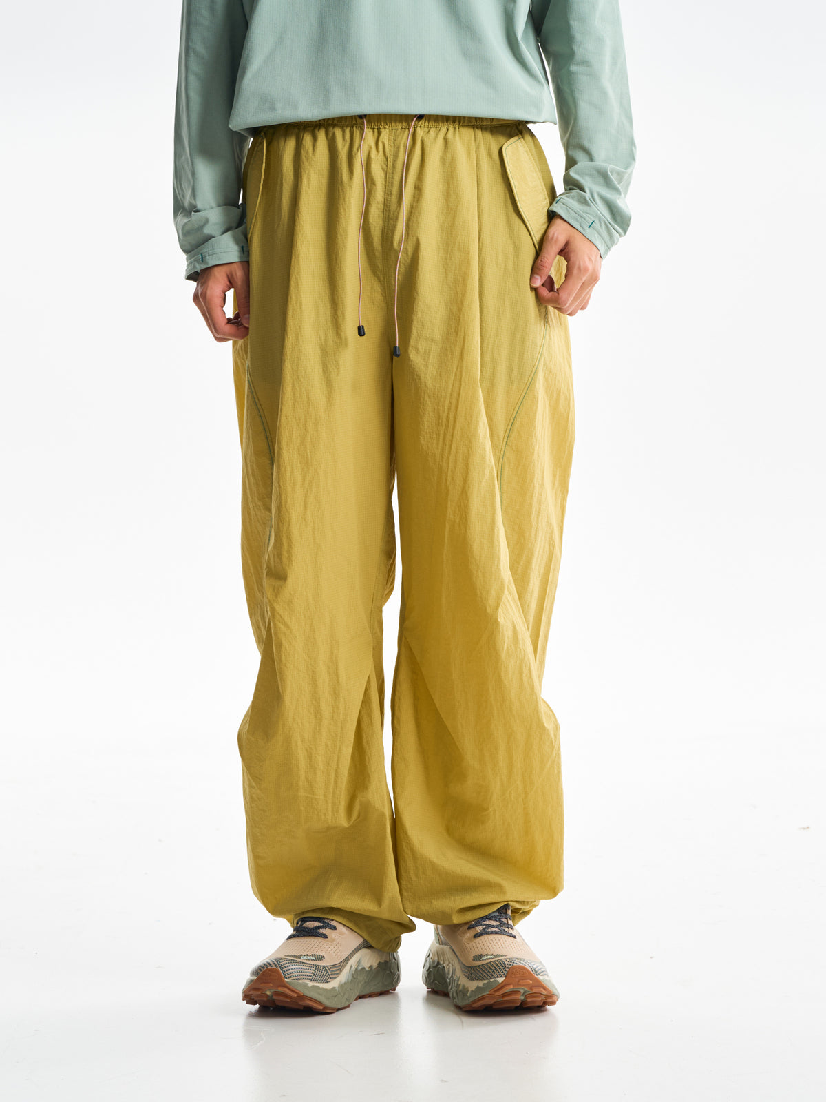 Yellow hiking pants — front view showing the long waist cords and roomy legs