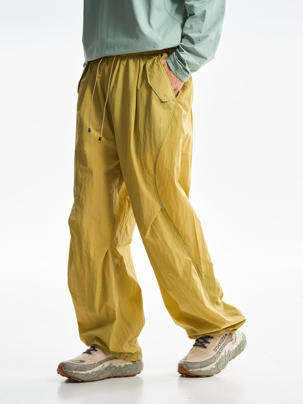 Yellow hiking pants — side stride showing the curved leg seam and loose folds