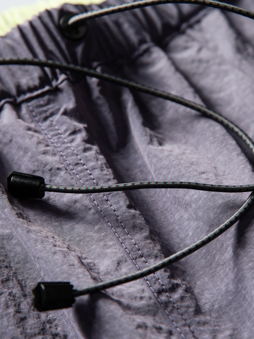 Purple hiking pants — close-up of the waist drawcord ends and gathered waistband