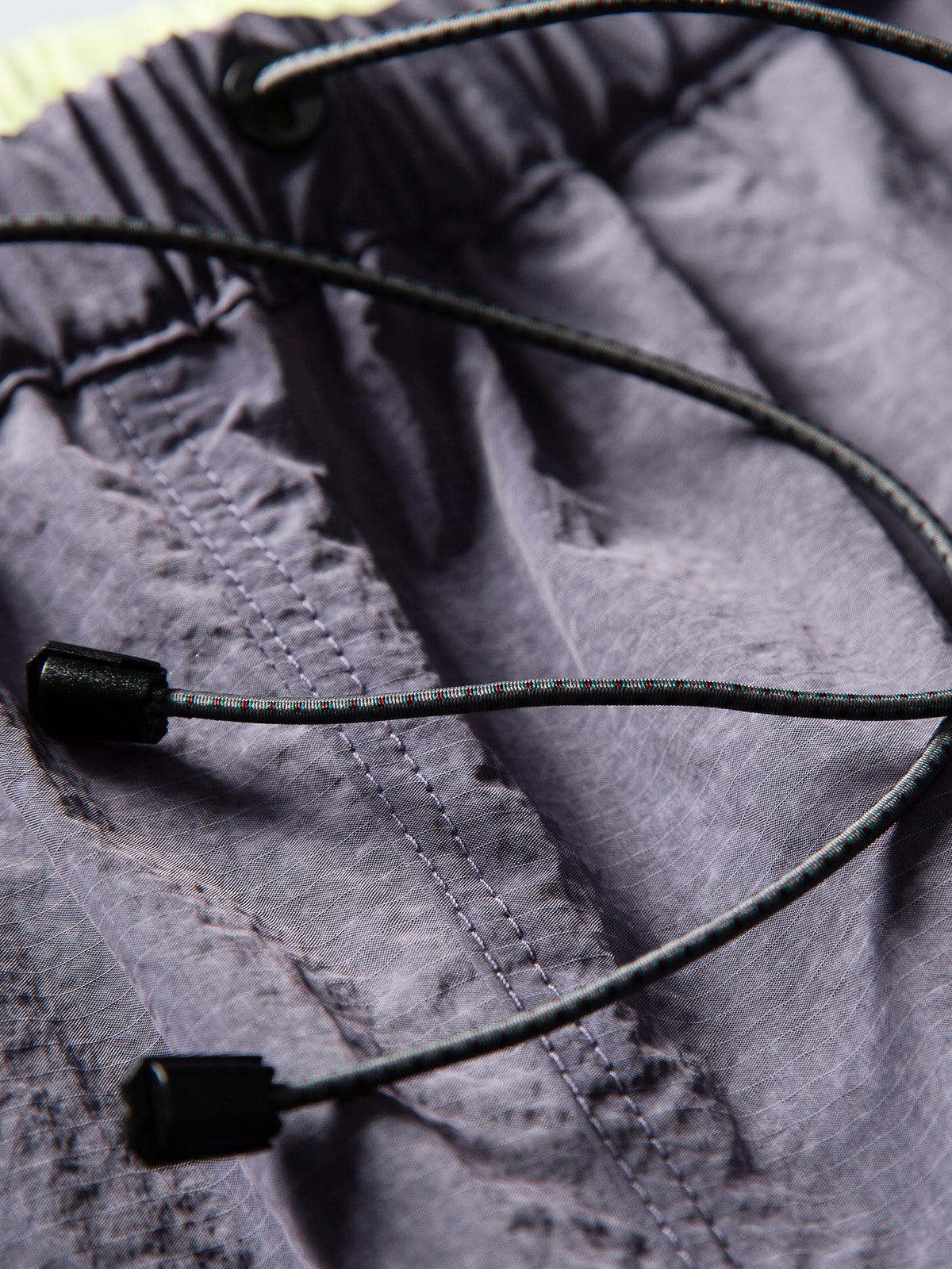 Purple hiking pants — close-up of the waist drawcord ends and gathered waistband