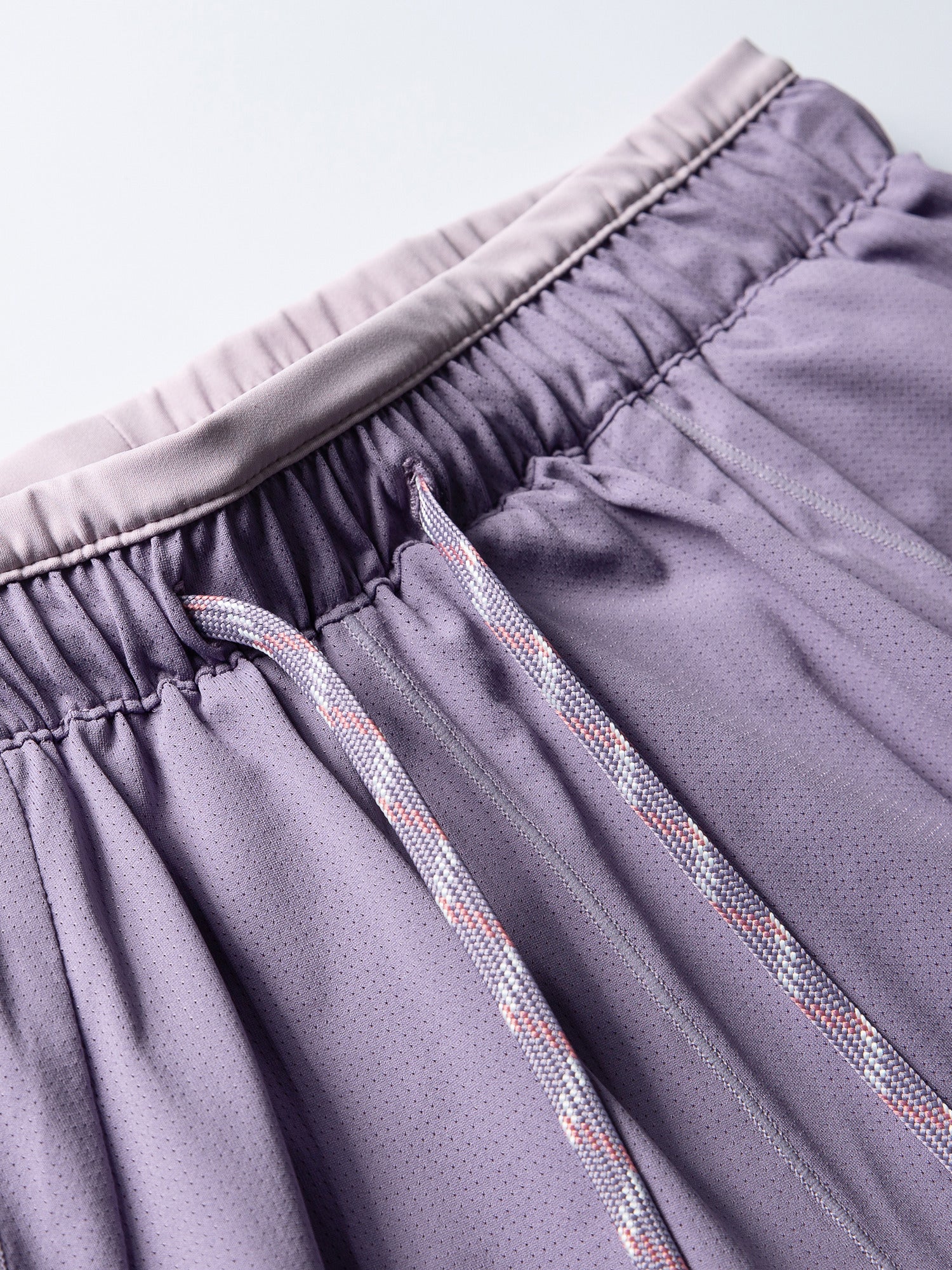 Purple hiking shorts — elastic waistband stitching and drawcord attachment