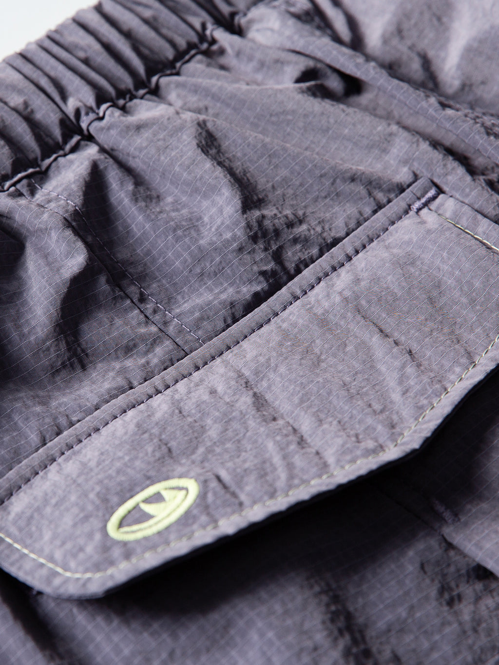 Purple hiking pants — close-up of the rear pocket flap and its stitched edge