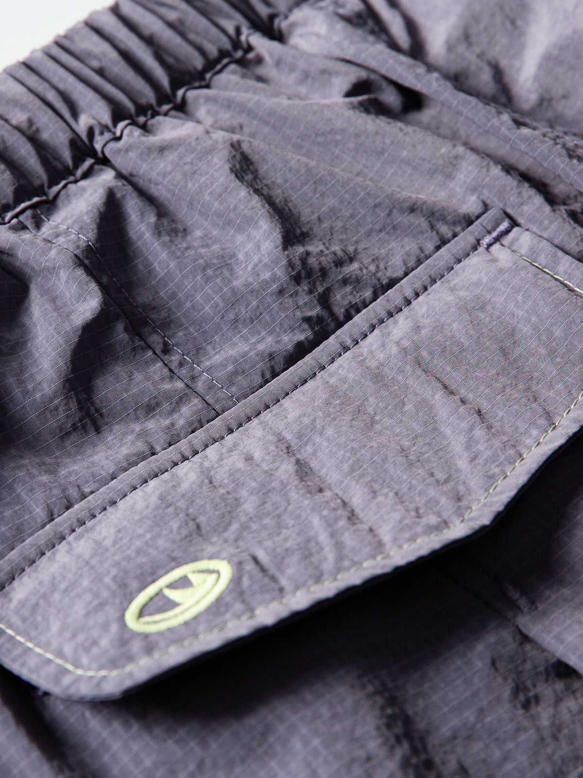 Purple hiking pants — close-up of the rear pocket flap and its stitched edge