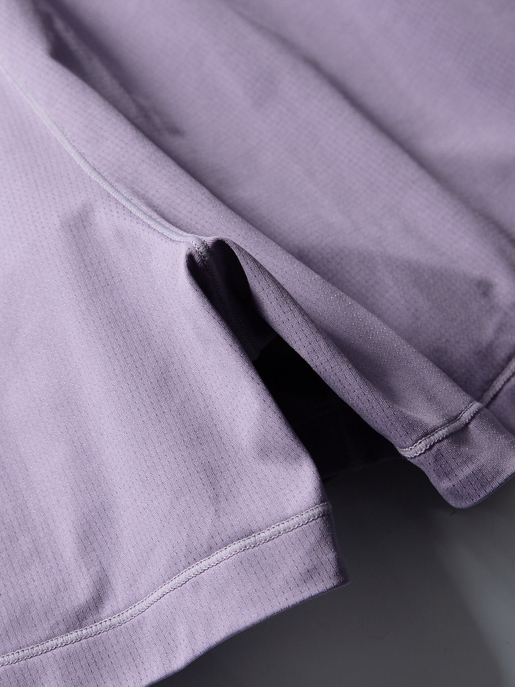 Purple hiking shorts — close-up of the perforated shell texture and curved seam