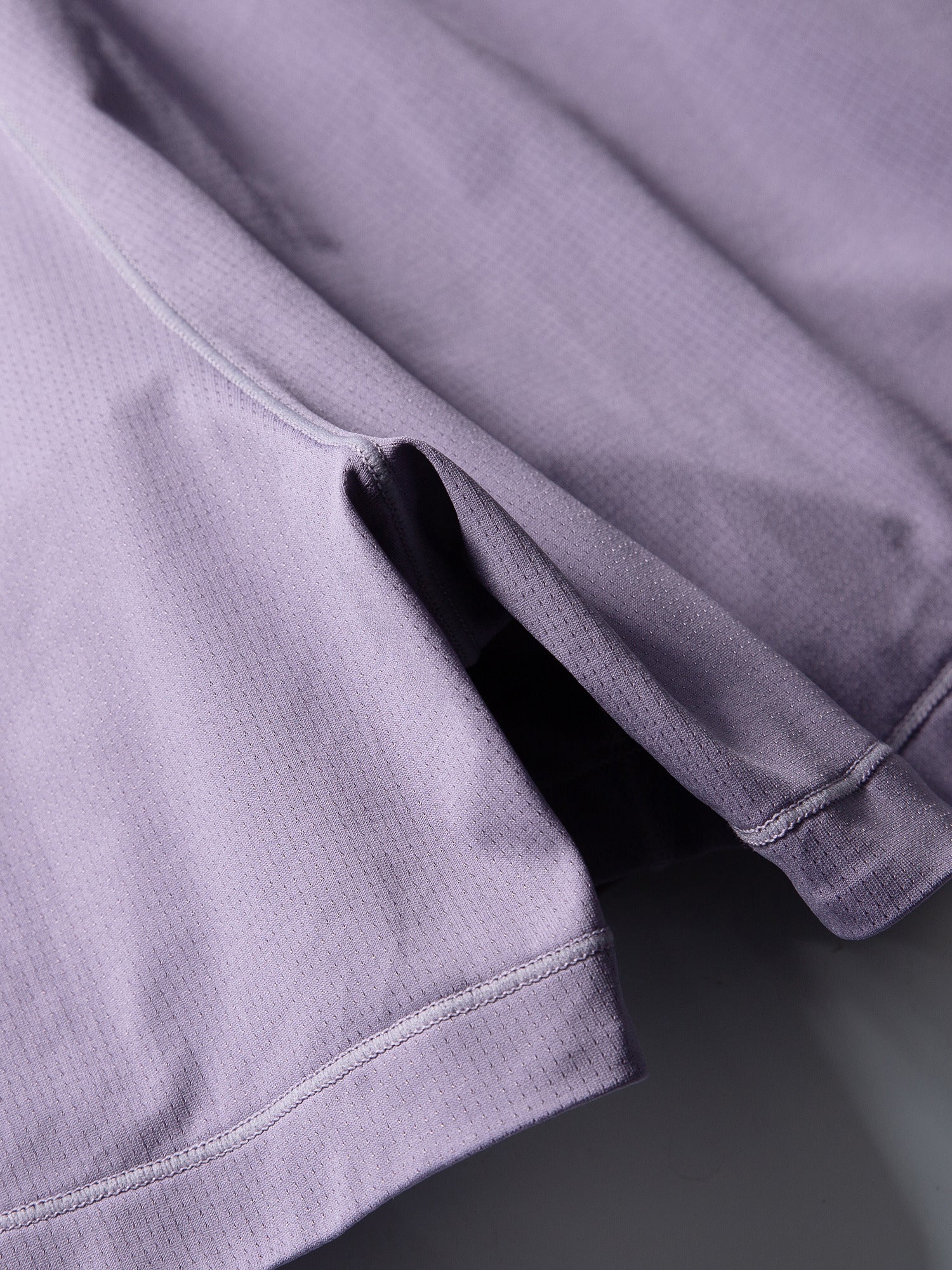 Purple hiking shorts — close-up of the perforated shell texture and curved seam