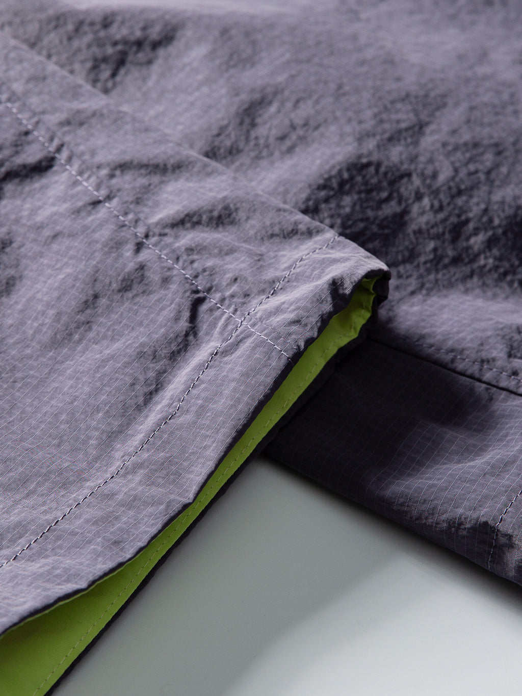Purple hiking pants — overlapping open hem edges with contrasting lining and stitching