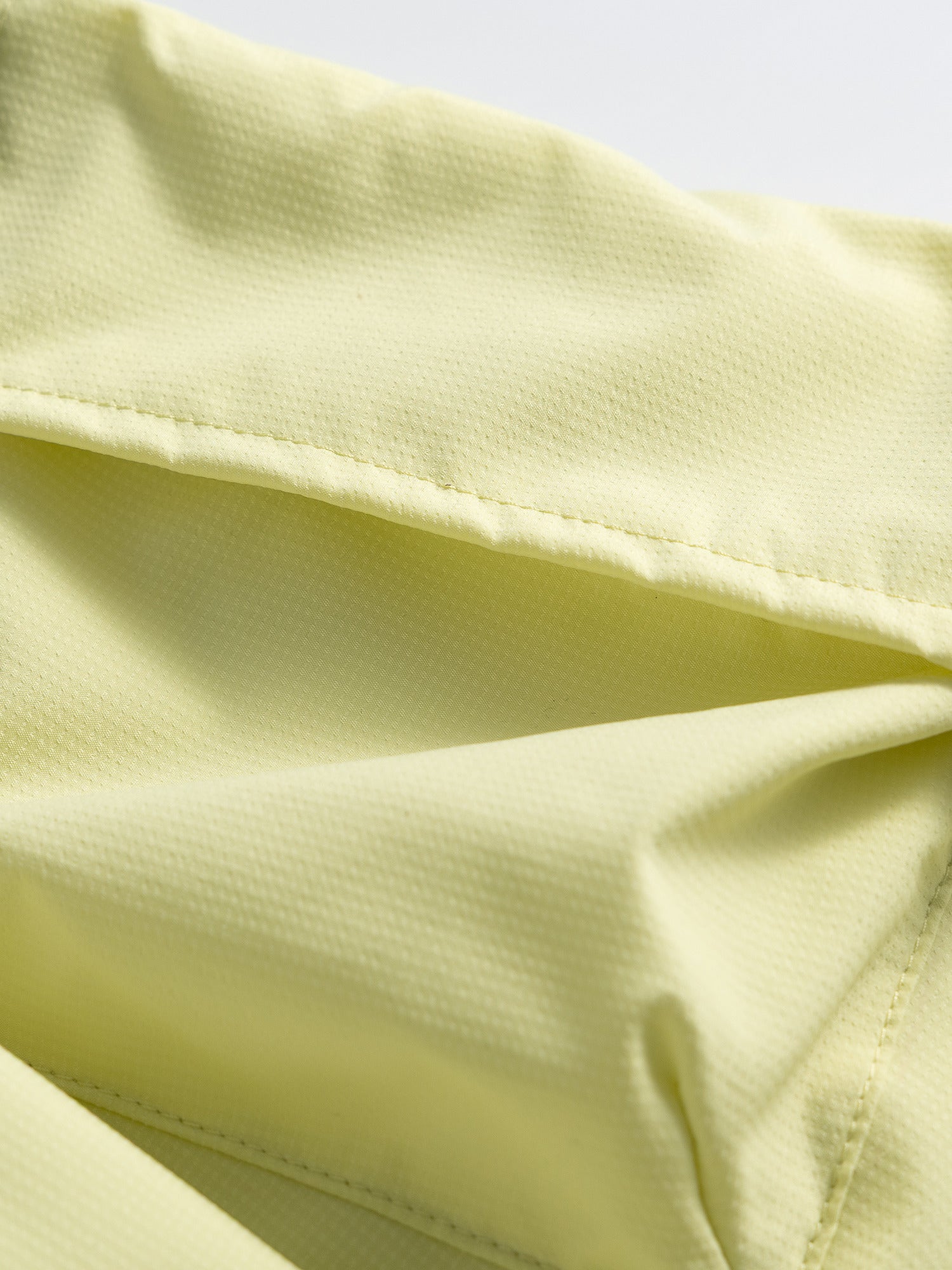 Yellow hiking capri pants — close-up of the cargo flap stitching and central pocket pleat
