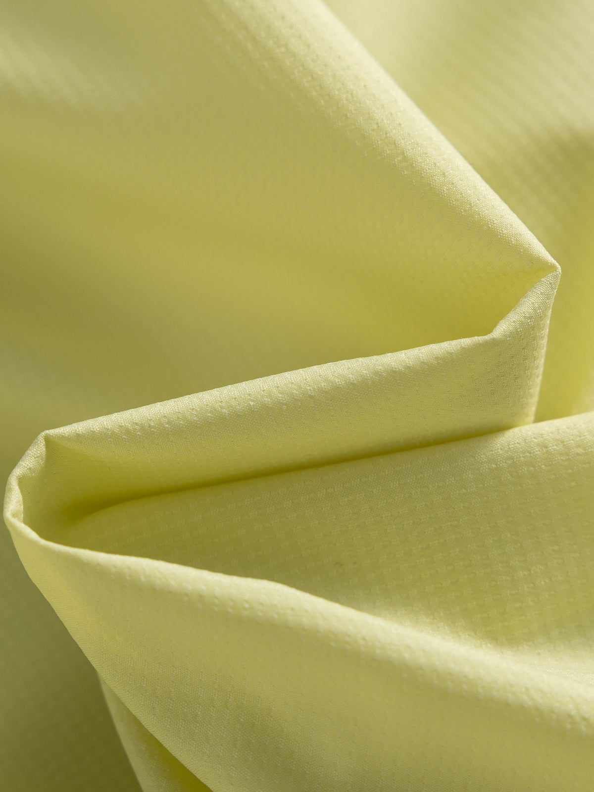 Yellow hiking capri pants — close-up of the fine grid texture across folded fabric