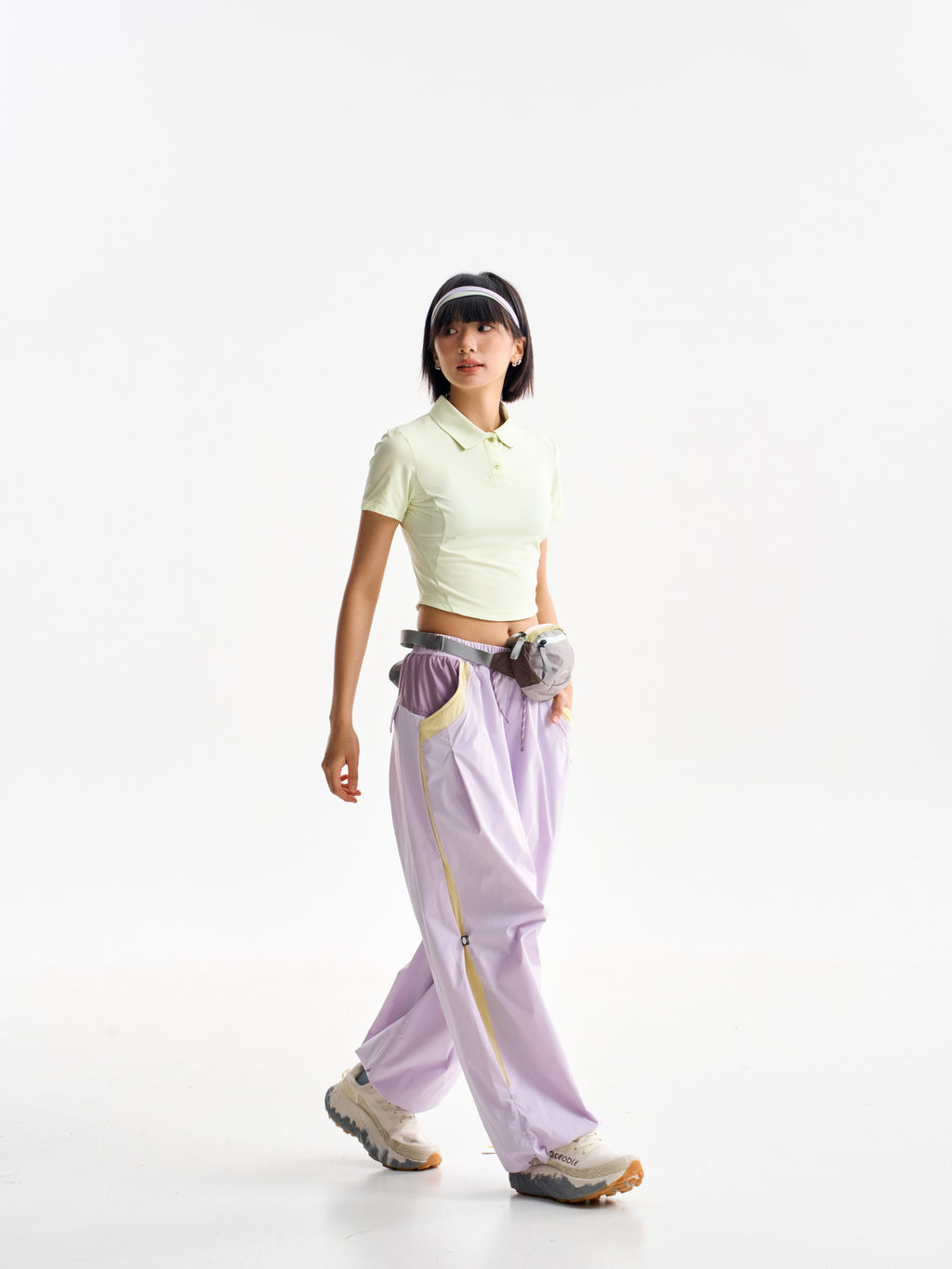 Purple Pink hiking pants — walking view showing yellow side trim below a waist bag