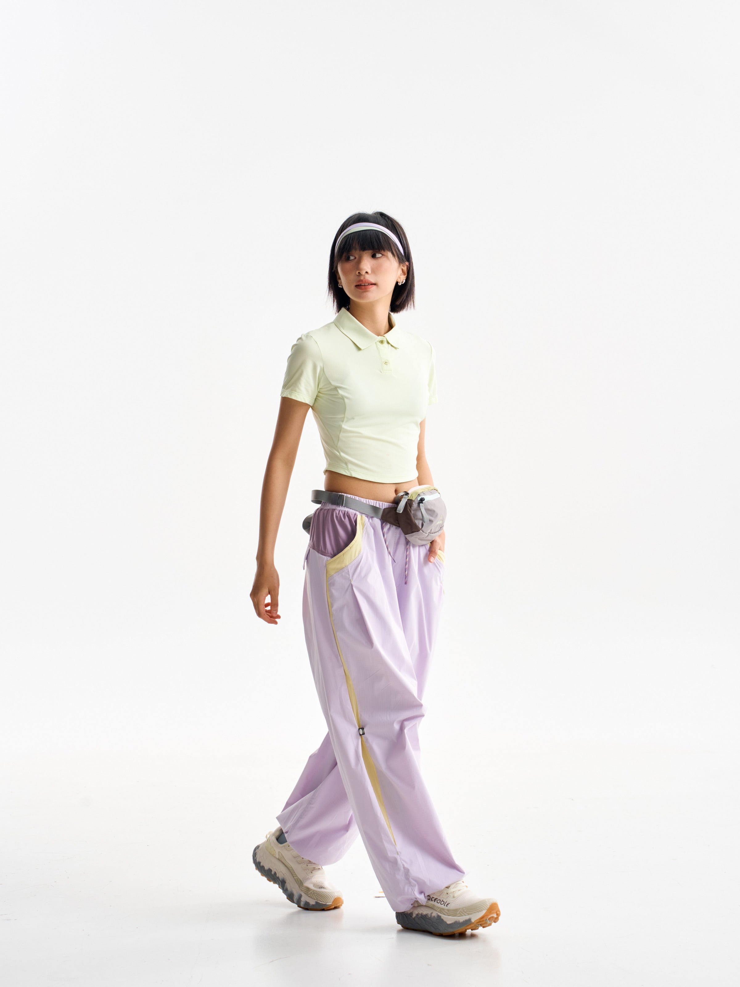 Purple Pink hiking pants — walking view showing yellow side trim below a waist bag