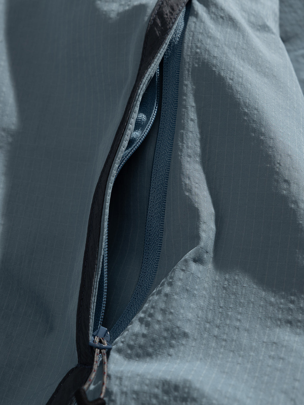Blue jacket — open zip pocket with the zip teeth and edge stitching visible