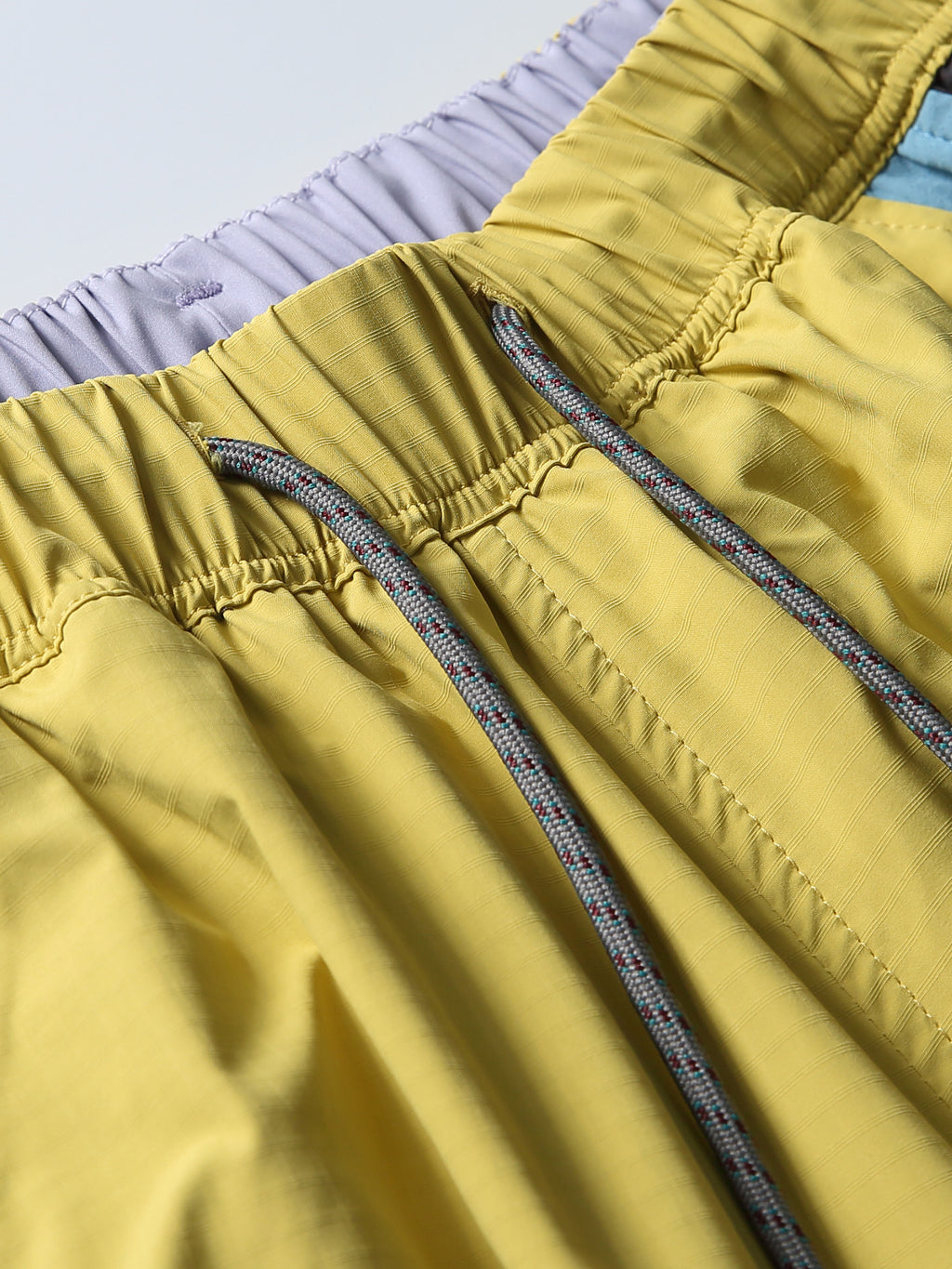 Yellow hiking pants — elastic waistband stitching and drawcord exits