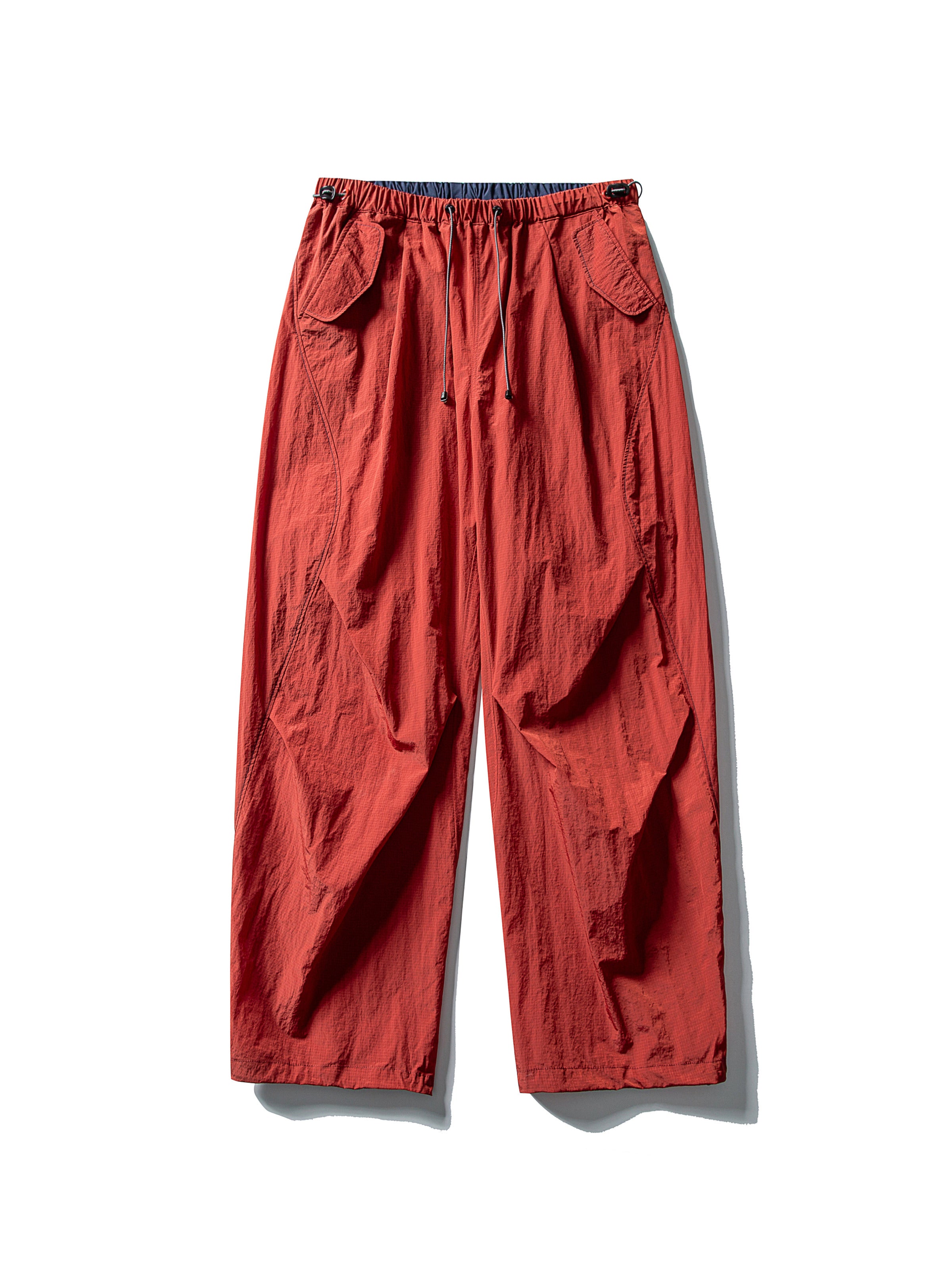 Red hiking pants — flat front view showing the brick-red shell and dark waist edge