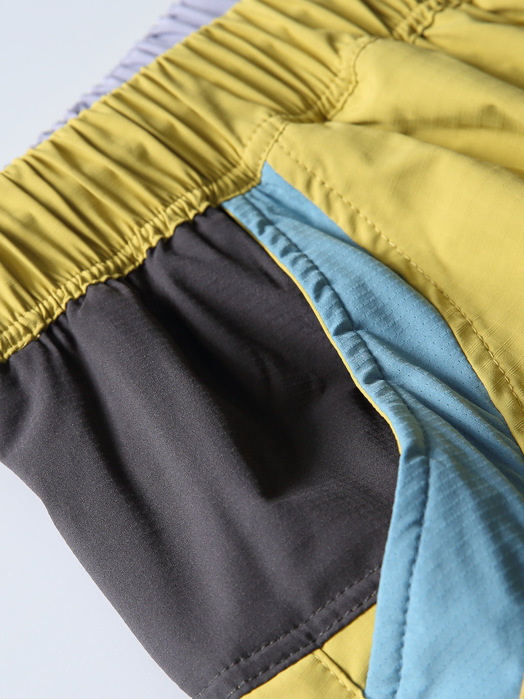Yellow hiking pants — curved pocket opening with blue and black contrast panels