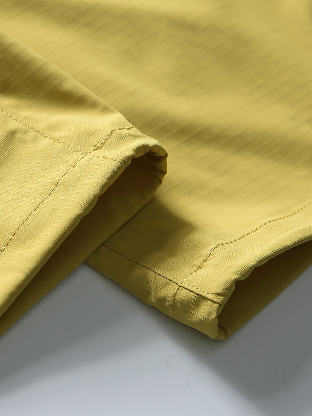 Yellow hiking pants — open hem edge and stitching with the fabric laid flat