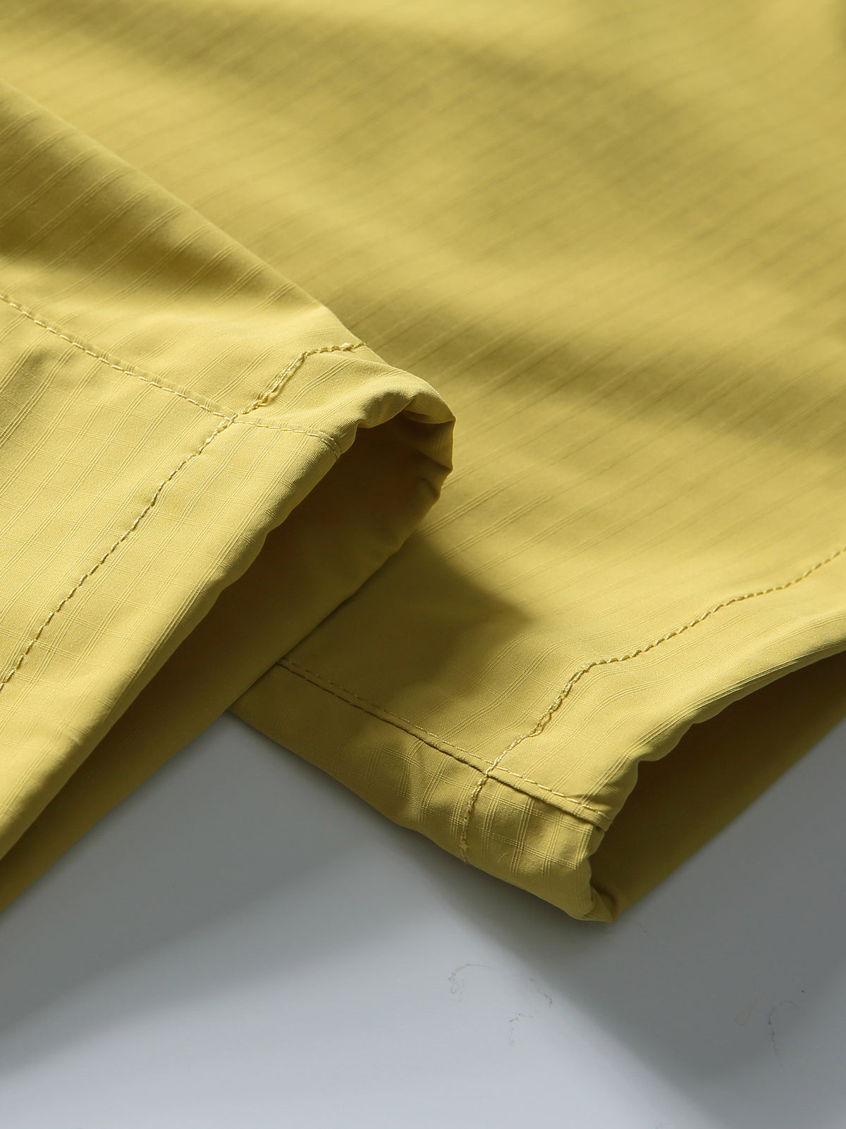 Yellow hiking pants — open hem edge and stitching with the fabric laid flat