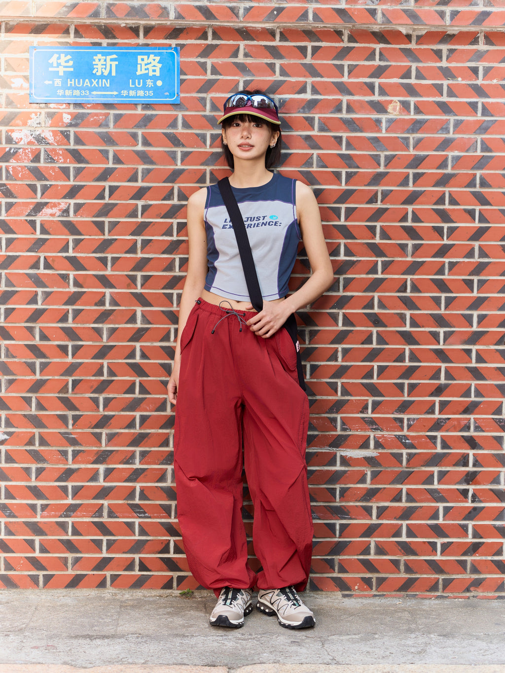 Red hiking pants — outdoor front view beside a brick wall with the full leg shape visible
