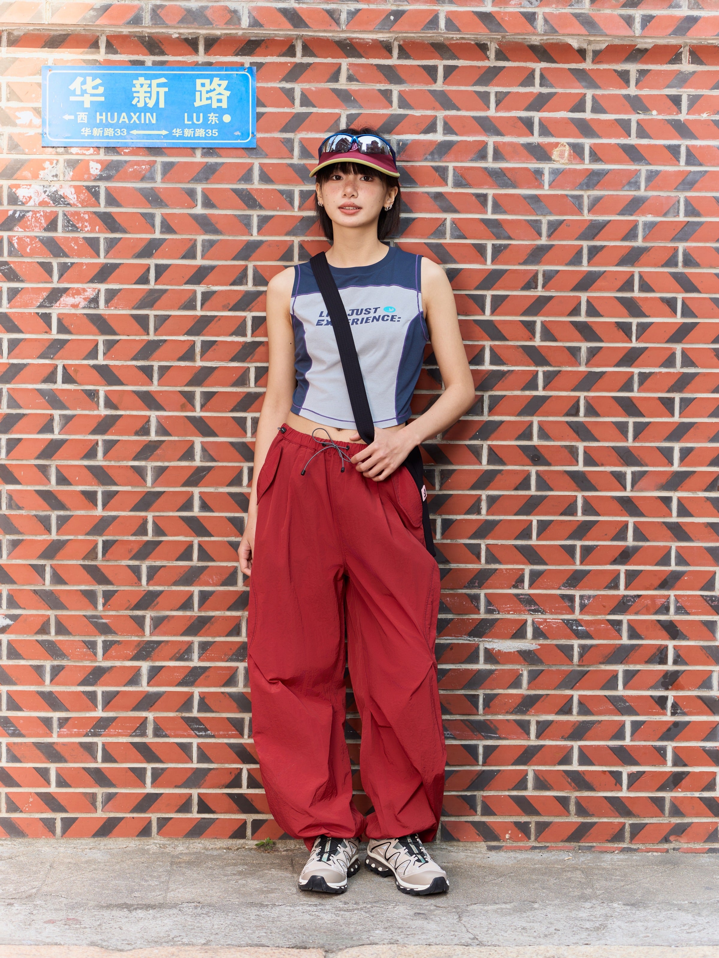 Red hiking pants — outdoor front view beside a brick wall with the full leg shape visible